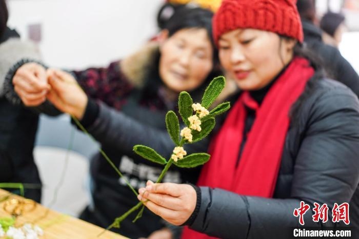 馮燕霞指導(dǎo)姐妹們鉤織月桂葉片。　古良駒 攝