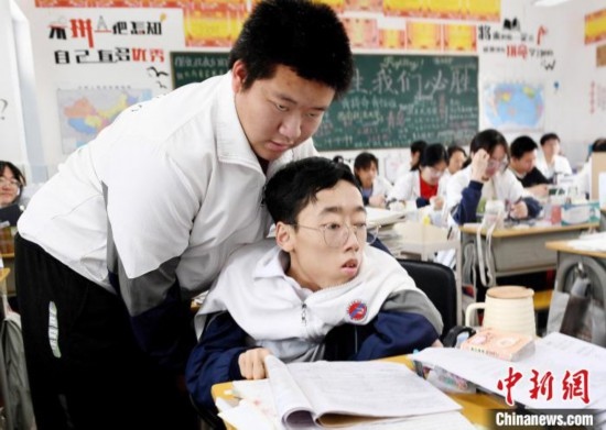 朱金祥(左)把鐘華強(qiáng)放到課堂座位上后，都要把他擺正好，確認(rèn)安全后才回到自己的座位上。 卓忠偉 攝