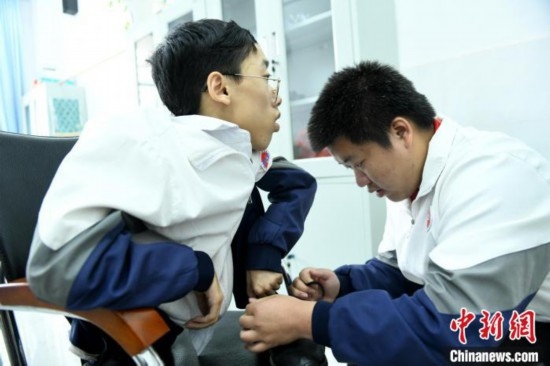 江西省南康中學(xué)北校區(qū)的高三學(xué)生朱金祥(右)正在給鐘華強(qiáng)(左)系好鞋帶。 卓忠偉 攝