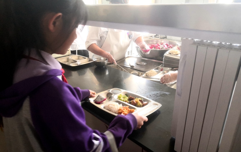 伊金霍洛旗第一小學(xué)學(xué)生正在打飯，今天的飯菜是三菜一湯外加水果，學(xué)生可以多次盛取，吃飽為止。人民網(wǎng)記者 孫博洋攝