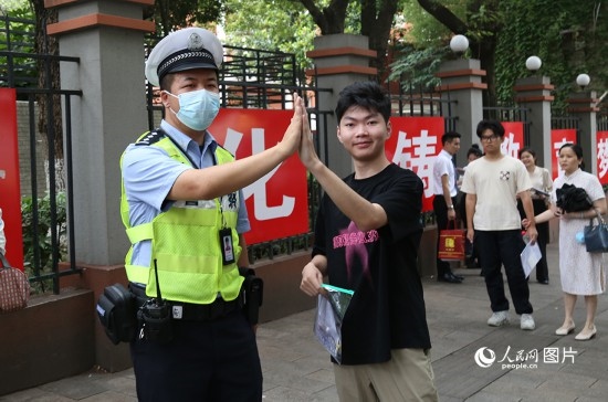 6月7日8時許，武漢中學(xué)考點門口，交警在維護(hù)秩序，并祝考生金榜題名。人民網(wǎng)記者 肖璐欣攝