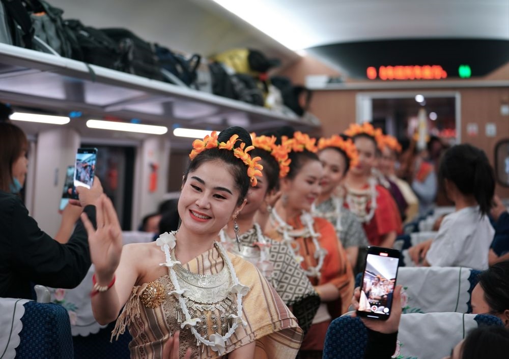 2023年4月13日，老撾工作人員在D887次國際旅客列車上表演。當日，中老鐵路從中國昆明南站、老撾萬象站雙向?qū)﹂_D887次和D888次國際旅客列車，兩地乘火車可當日通達。中老鐵路是高質(zhì)量共建“一帶一路”的標志性工程。新華社記者 邢廣利 攝