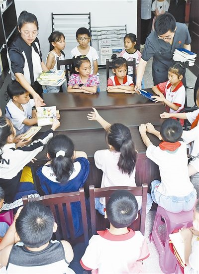  圖④：法院干警為留守兒童發(fā)放暑假讀物。