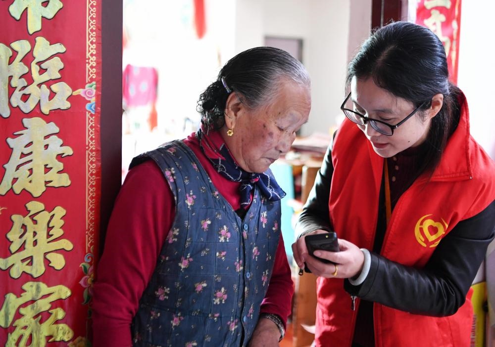 在福州市長(zhǎng)樂(lè)區(qū)航城街道籌岐村，智慧養(yǎng)老平臺(tái)派駐社區(qū)的助老員（右）在為老人陳鳳英（左）講解養(yǎng)老定制手機(jī)的用法（2021年11月26日攝）。新華社記者 魏培全 攝