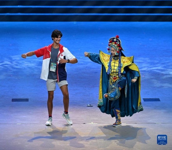 7月29日，美國運動員杜恩（左）在聯(lián)歡會現(xiàn)場與川劇演員互動。新華社記者 蔡湘鑫 攝