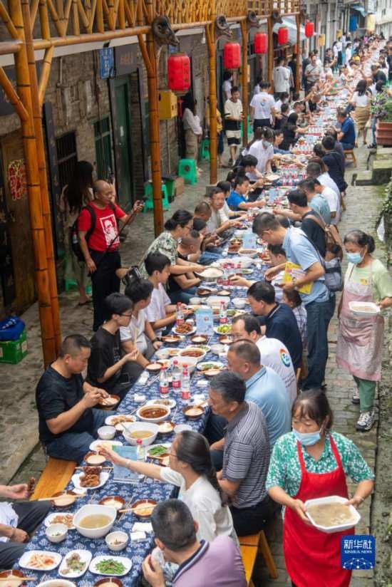 7月29日，在重慶市綦江區(qū)安穩(wěn)鎮(zhèn)，人們在“苗家伏羊節(jié)”上吃長桌宴。新華社記者 唐奕 攝