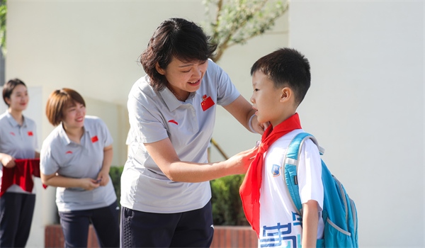 8月30日，雄安史家胡同小學(xué)學(xué)生體驗(yàn)學(xué)校生活。老師為學(xué)生佩戴?；?。