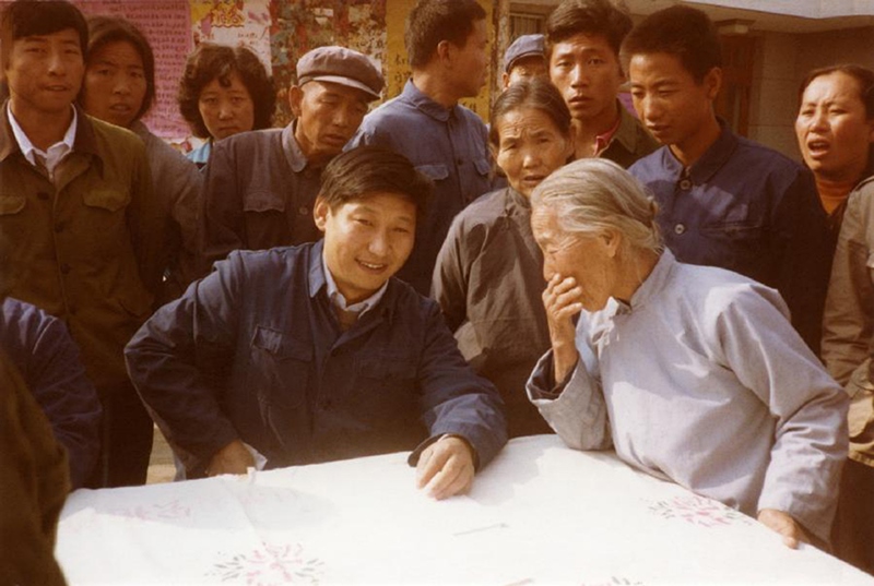 1983年，時(shí)任河北正定縣委書記的習(xí)近平（前排居中）臨時(shí)在大街上擺桌子聽取老百姓意見。