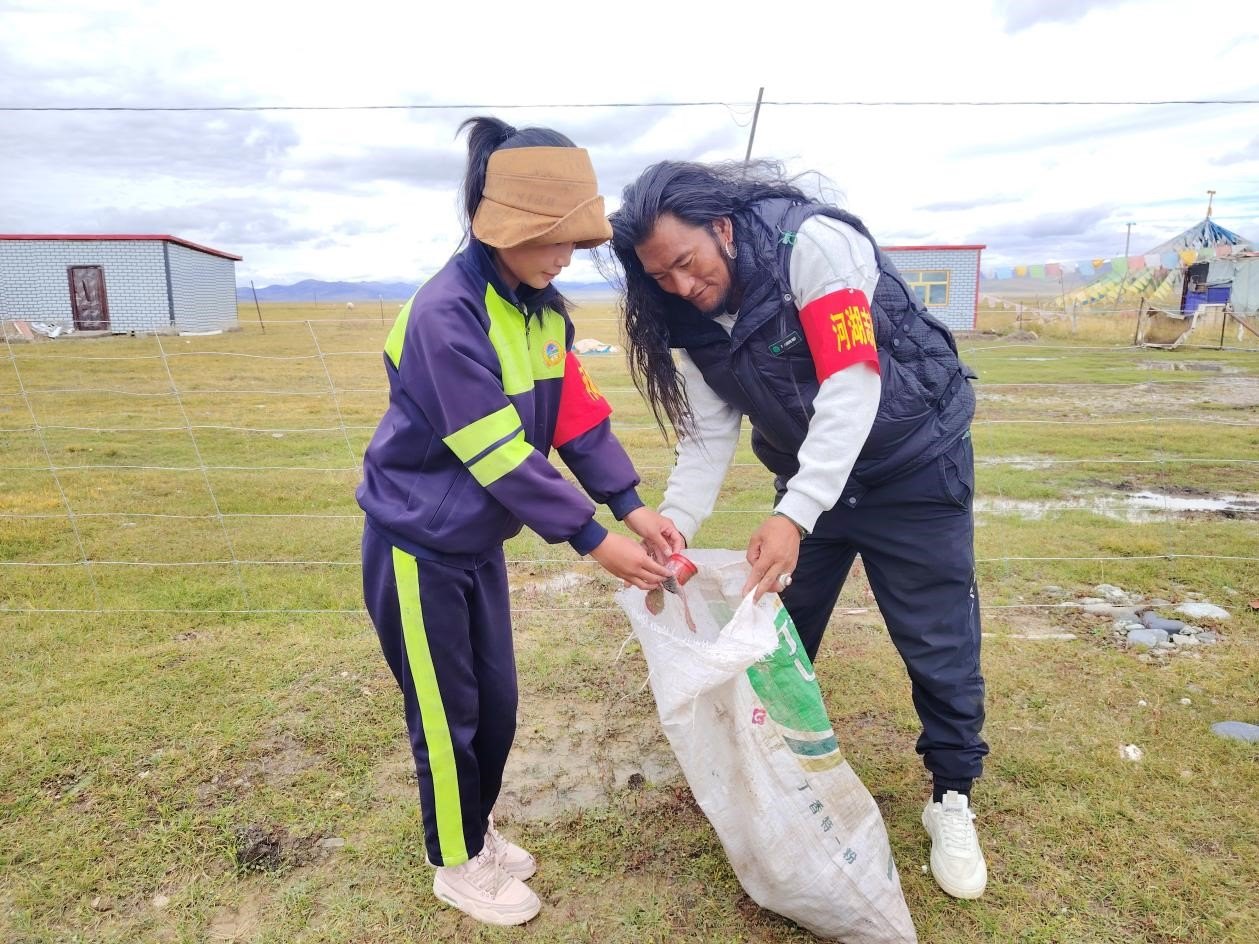 玉樹州稱多縣珍秦鎮(zhèn)河湖志愿者才培和他女兒更求拉毛在清掃垃圾。受訪者供圖
