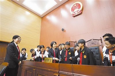 圖③：同學(xué)們穿法袍、敲法槌，爭做“小法官”。