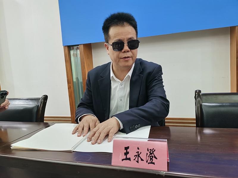 全國人大代表王永澄正在閱讀盲文版代表建議答復(fù)。本報記者 張 璁攝