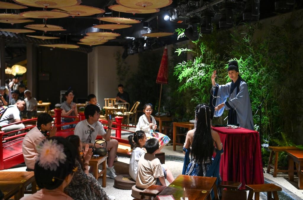 游客在長(zhǎng)安十二時(shí)辰主題街區(qū)觀看唐風(fēng)演藝《大唐曲藝》。新華社記者鄒競(jìng)一 攝