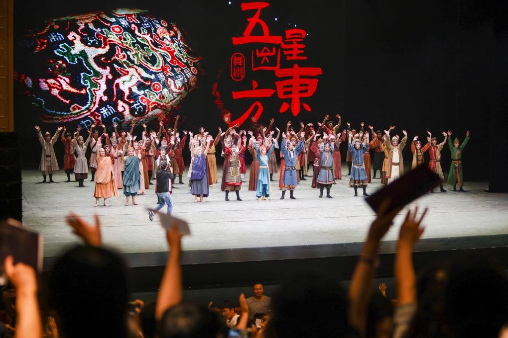 2023年7月31日，新疆和田地區(qū)新玉歌舞團在烏魯木齊京劇院演出舞劇《五星出東方》后和觀眾互相揮手致意。這場演出是第六屆中國新疆國際民族舞蹈節(jié)的參演劇目之一，曾榮獲國家“文華獎”等。新華社記者 郝昭 攝