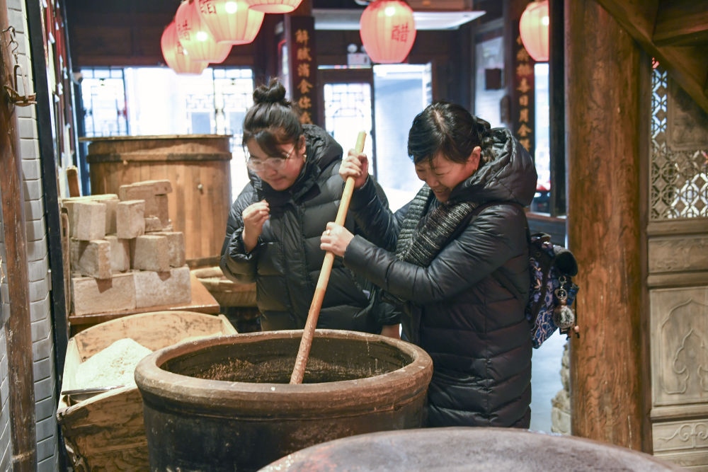 游客在平遙古城東湖老醋坊內(nèi)體驗(yàn)陳醋發(fā)酵打耙（2022年1月28日攝）。新華社發(fā)（梁生仁攝）