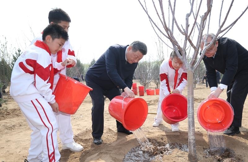 2024年4月3日，習近平總書記同少先隊員一起給剛栽下的樹苗澆水。