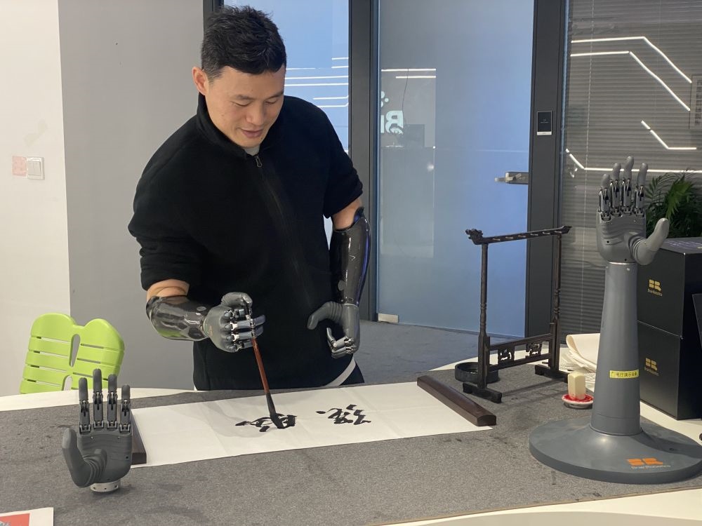 2024年3月29日，在浙江強腦科技有限公司展廳內(nèi)，失去雙手的產(chǎn)品體驗官倪敏成依靠智能仿生手寫毛筆字。新華社記者 魏一駿 攝