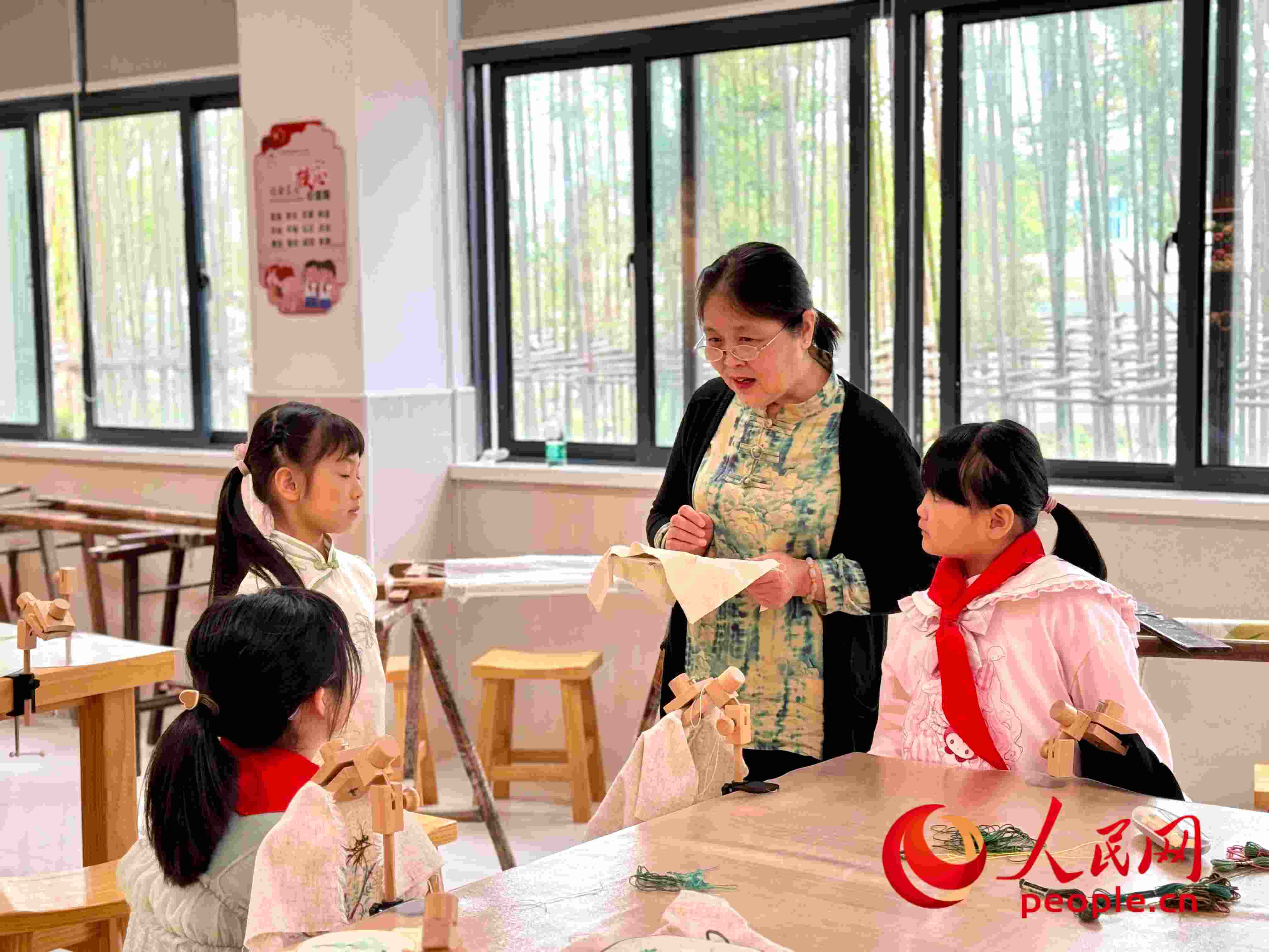 顧建珍（左三）在教孩子們刺繡知識。人民網(wǎng) 周靜圓攝