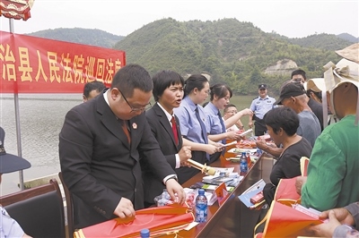 法院干警及相關(guān)部門工作人員對(duì)群眾進(jìn)行生態(tài)環(huán)境保護(hù)普法教育。