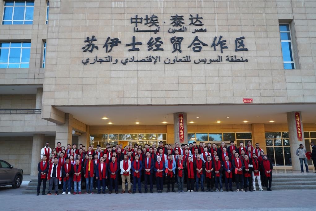 2024年2月11日，在位于埃及蘇伊士省的中埃·泰達蘇伊士經(jīng)貿(mào)合作區(qū)，中埃員工在合作區(qū)辦公大樓前合影拜年。新華社發(fā)（泰達合作區(qū)供圖）