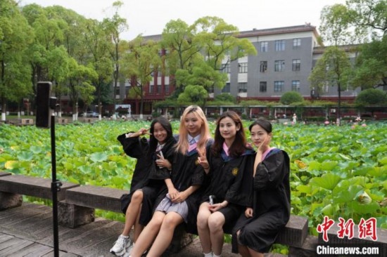6月19日，時(shí)值一年畢業(yè)季，四川大學(xué)望江校區(qū)荷花池里的荷花盛開(kāi)，成為了畢業(yè)生們的打卡圣地，吸引了眾多畢業(yè)生拍照留念。圖為畢業(yè)生在荷花池邊拍照留念。中新社記者 安源 攝