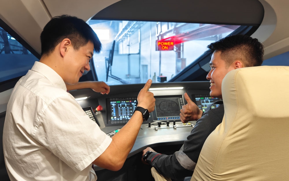 2023年8月25日，在印度尼西亞萬隆的雅萬高鐵德卡魯爾動車所內(nèi)，中國師傅穆振（左）向印尼火車司機(jī)塞蒂亞萬講解動車組出庫前的上電作業(yè)。新華社記者 徐欽 攝