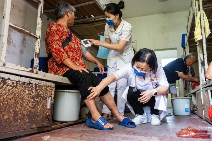 2024年7月30日，在湖南省湘潭縣河口中學安置點，醫(yī)務人員為受洪水影響而轉(zhuǎn)移安置的群眾檢查身體。 新華社記者 陳思汗 攝