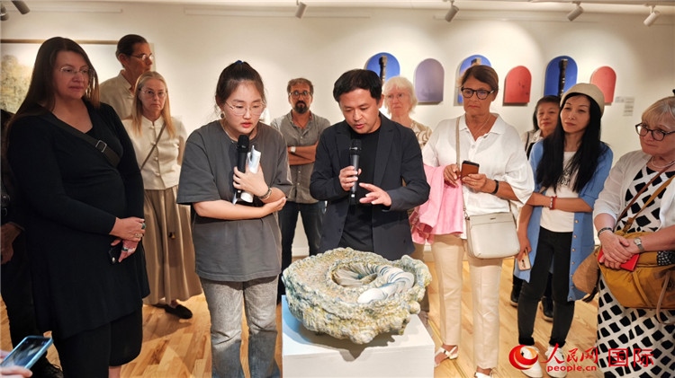 參展人、景德鎮(zhèn)陶瓷大學(xué)設(shè)計(jì)藝術(shù)學(xué)院副院長(zhǎng)余劍峰（中）向來(lái)賓介紹參展作品。人民網(wǎng)記者 殷淼攝
