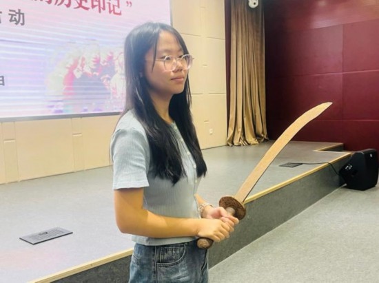 圖為南開大學(xué)社會(huì)實(shí)踐隊(duì)學(xué)生代表呼月紅在學(xué)術(shù)交流活動(dòng)現(xiàn)場(chǎng)，展示河間調(diào)研行中獲贈(zèng)的一戰(zhàn)華工蔡世春曾使用過(guò)的一把大刀。林卓瑋 攝