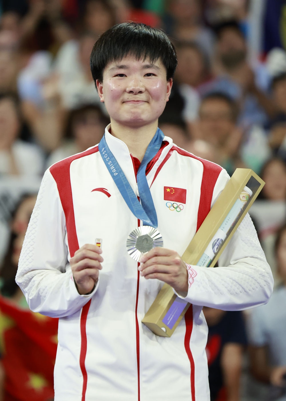 巴黎奧運會羽毛球女子單打亞軍、中國選手何冰嬌在頒獎儀式上一手握著銀牌，一手握著西班牙奧委會徽章（2024年8月5日攝）。新華社記者 任正來 攝
