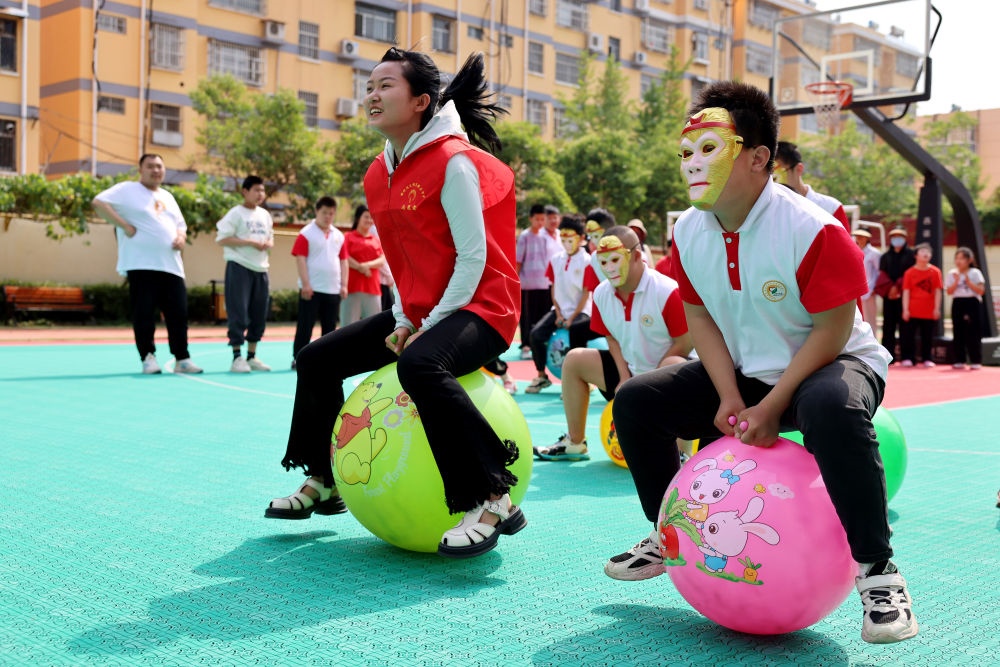 2024年5月17日，在山東省棗莊市市中區(qū)特殊教育中心，青年志愿者與智力障礙學(xué)生一起做游戲。新華社發(fā)（孫中喆攝）