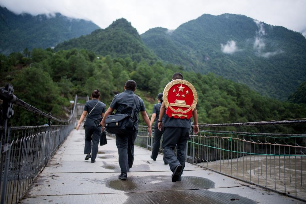 云南省怒江傈僳族自治州貢山縣人民法院法官鄧興背著國徽與同事們跨過怒江（2019年8月30日攝）。怒江高山峽谷眾多，交通不便，為方便群眾、更好地開展法律服務(wù)，背著國徽攀高山、過索橋、躲落石、鉆老林……成為鄧興法官的工作常態(tài)。新華社記者 江文耀 攝