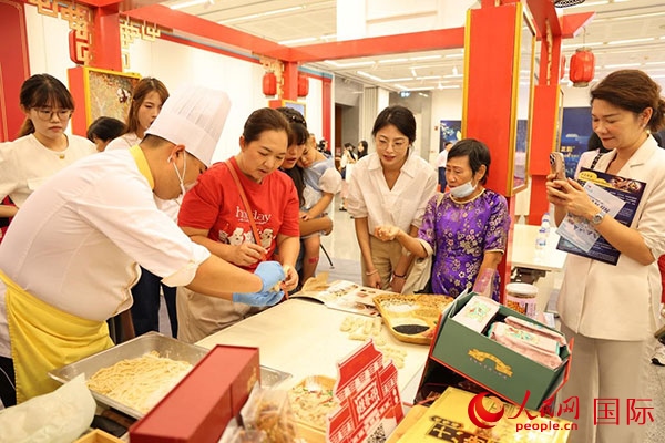 演出前，在天津桂發(fā)祥十八街麻花制作技藝非遺體驗展臺前，泰國民眾體驗天津麻花制作。人民網(wǎng)記者 楊一攝