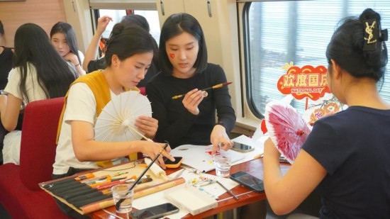 10月1日，旅客們在G1634次列車上給油紙傘作畫。新華社記者周義 攝