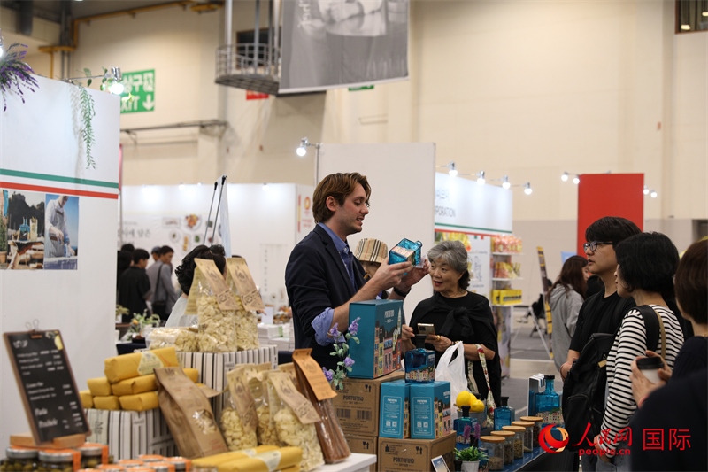 當(dāng)?shù)貢r間10月5日，在第21屆釜山國際美食博覽會上，意大利展商向參觀者們介紹的意大利食品。人民網(wǎng)記者 莽九晨攝