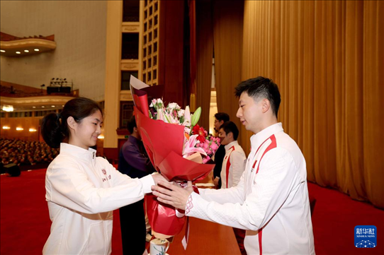 11月15日，一名學(xué)生代表在報(bào)告會上向乒乓球運(yùn)動員馬龍（右）獻(xiàn)花。新華社記者 李明 攝