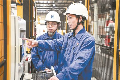 在廣西柳工機(jī)械股份有限公司生產(chǎn)車(chē)間內(nèi)，一名高級(jí)技師（右）給徒弟講解數(shù)控設(shè)備操作細(xì)節(jié)。新華社記者 曹祎銘攝