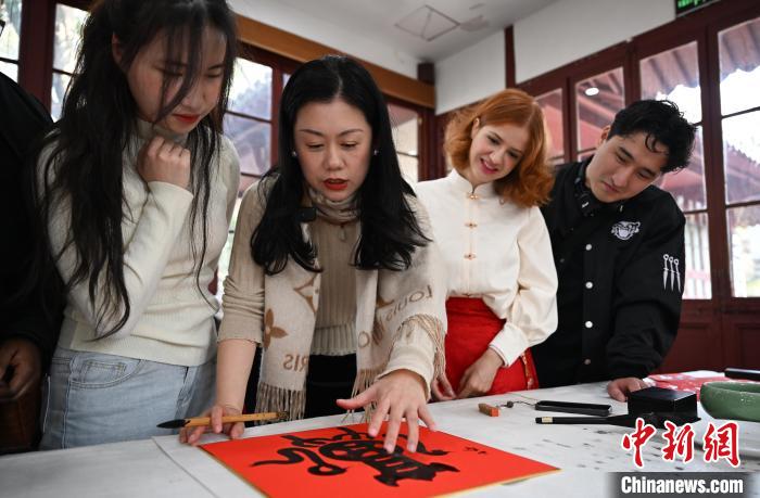 1月20日，西泠印社社員李硯（左二）為外籍留學(xué)生講述蛇年福字貼創(chuàng)作靈感。當(dāng)日，來自巴西、馬來西亞、加納、哈薩克斯坦的外籍留學(xué)生在浙江杭州西泠印社體驗(yàn)福貼、春聯(lián)和篆刻，感受古老的中國傳統(tǒng)文化。中新社記者 王剛 攝