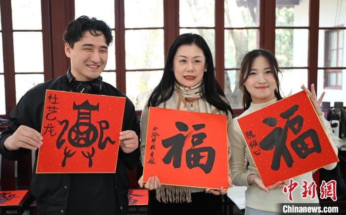 1月20日，外籍留學(xué)生和西泠印社社員李硯(中)展示各自創(chuàng)作的福貼。當(dāng)日，來自巴西、馬來西亞、加納、哈薩克斯坦的外籍留學(xué)生在浙江杭州西泠印社體驗(yàn)福貼、春聯(lián)和篆刻，感受古老的中國傳統(tǒng)文化。中新社記者 王剛 攝