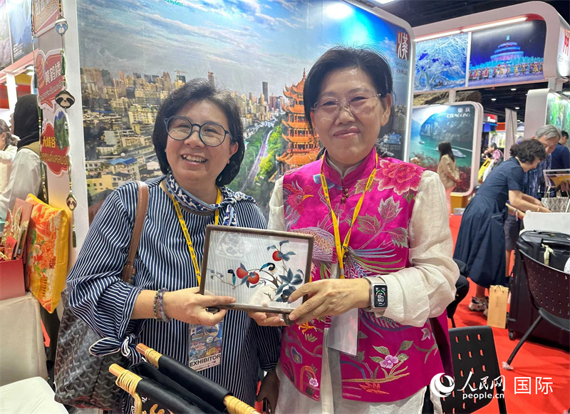 中國“大冶刺繡”傳承人劉小紅（右）參加泰國國際旅游展，向觀眾介紹中國非遺刺繡針法。人民網(wǎng)記者 簡承淵攝