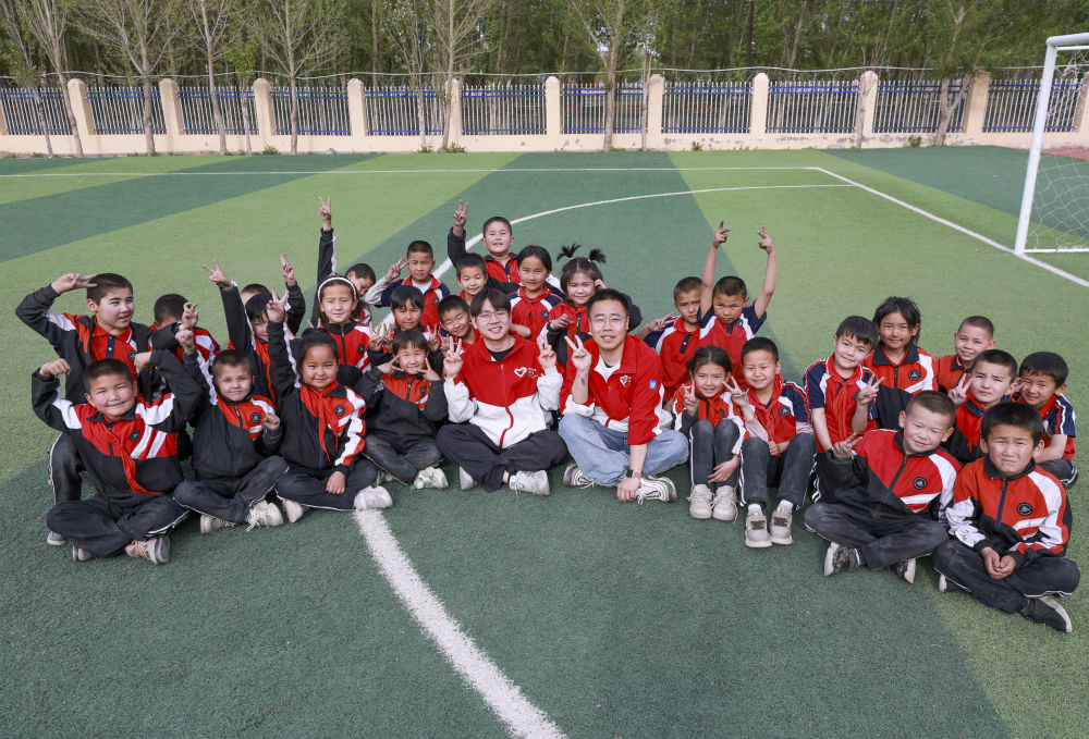 4月23日，在新疆克州阿圖什市哈拉峻鄉(xiāng)謝依特小學(xué)，支教教師王俊文（中左）、李軻凡（中右）和學(xué)生在一起。